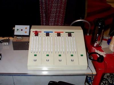 Control panel used in a game show setting with multiple sliders and buttons.