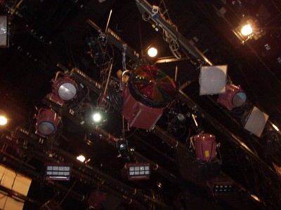 Ceiling view of stage lights and equipment in a studio setting.
