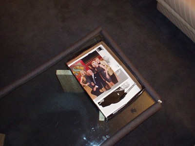 A photo laying on a glass table showing three people at a studio, with a colorful backdrop and a black object partially obscuring one corner.