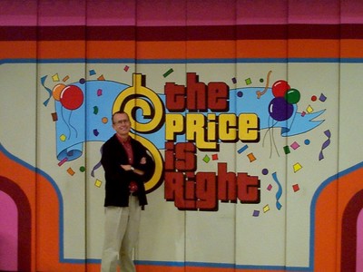 Roger Dobkowitz standing in front of the 'The Price is Right' game show set with colorful decorations and a festive backdrop.
