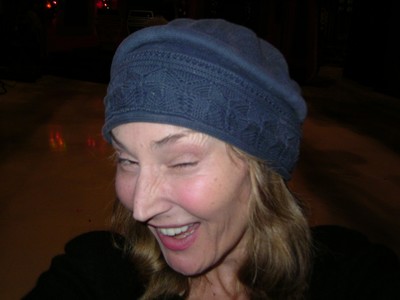 Mira Wilder wearing a blue hat is smiling and winking, capturing a playful and cheerful moment.