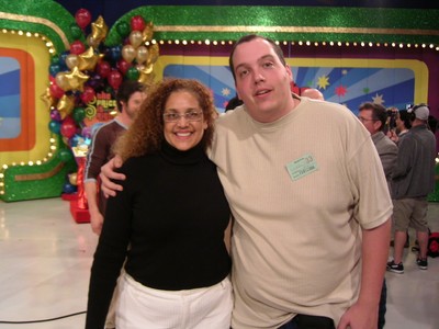 Denise Palm Stones and Marc Green posing for a photo on the set of The Price is Right, surrounded by colorful decorations and balloons.