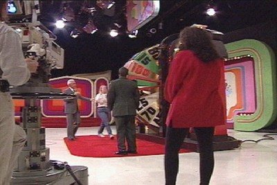 Inside CBS Television City's Stage 33, a game show scene with contestants and The Big Wheel, captured from behind a camera crew.