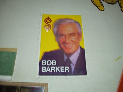A poster of Bob Barker featuring his smiling face on a yellow background with a dollar sign.