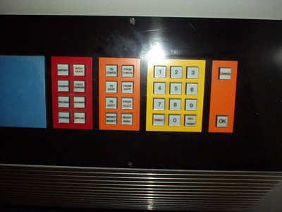 Close-up of a control panel featuring various buttons in red, blue, yellow, and orange colors, including number keys and function labels.