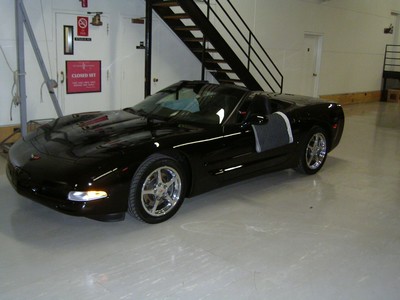 A black convertible sports car parked indoors near a staircase.