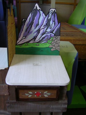 A colorful prop featuring a mountain backdrop with greenery and a drawer in front.
