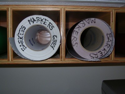 Rolls of colored paper labeled for props storage, including 'GREY' and 'BARRETT'.