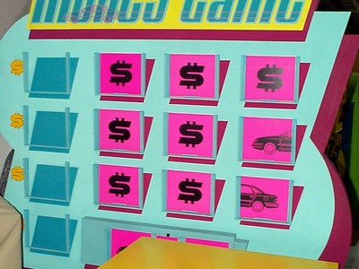 A colorful display board for Money Game, featuring rows of boxes with dollar signs and icons, including a car graphic.