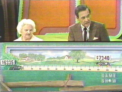A game show host stands next to a contestant, pointing at a visual display showing prices of cars on the colorful set of It's Optional.