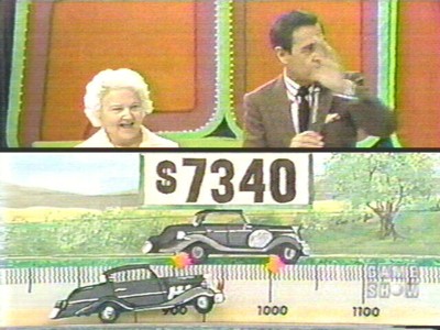 A vintage game show scene featuring a host and a contestant, with a display showing the price of $7340 and illustrations of cars in a landscape.