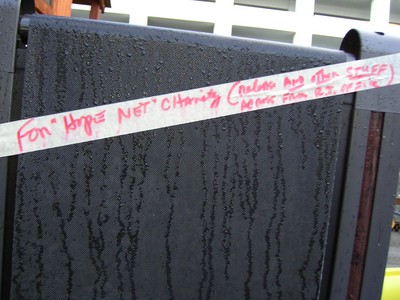 A close-up of a wet tape on a black surface, reading "For 'Hope NET' Charity (include any other stuff)" in red ink.