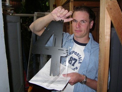 Man holding a transparent number four prop in a backstage setting.