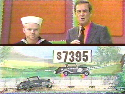 A vintage game show scene featuring a host and a contestant in a sailor outfit, with a sign displaying the price of $7395 next to a painted car backdrop.