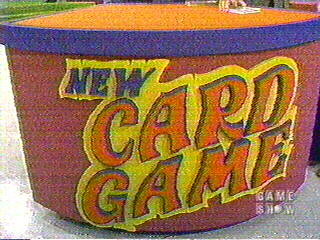 Colorful sign displaying 'NEW CARD GAME' from a game show set.