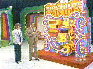 A colorful game show set featuring a host and a contestant beside the 'Pick a Pair' game display, adorned with lights and vibrant decorations.