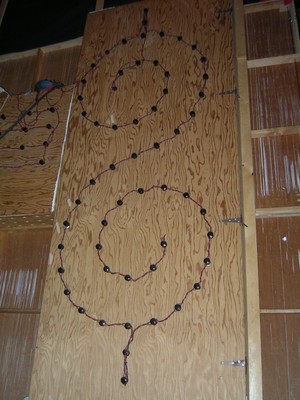 A wooden panel with a decorative arrangement of string lights forming a swirling pattern of a dollar sign on The Price is Right.