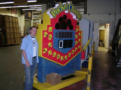 A person stands next to a colorful game display labeled 'Pocket Change' in a storage area at CBS Television City.