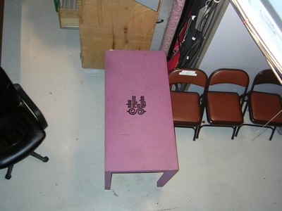 Aerial view of a purple table with an emblem in the center, surrounded by brown chairs and studio equipment.