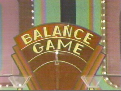 A close-up of the 'Balance Game' sign from The Price is Right, featuring bold lettering and colorful decorations in the background.