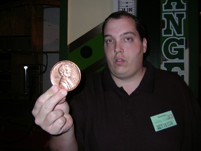 A person holding a large coin in a game show setting.