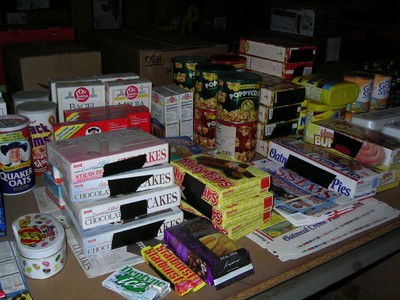 A variety of packaged food items, including cakes, snacks, and popcorn, displayed on a table in a studio setting.