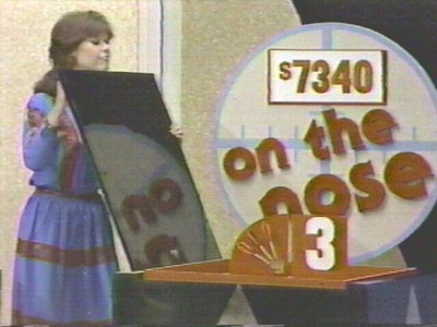 A participant reveals a game board for the game 'On the Nose' on The Price is Right, showcasing the prize amount of $7340.