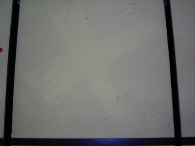 A close-up of a yellow surface with faint impressions resembling footprints, framed in black.