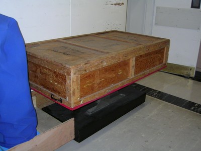 A wooden crate on a platform with a blue cover on the left side.