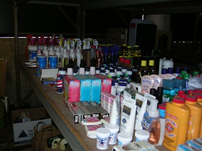 A table filled with various personal care and cosmetic products, including bottles of lotion, shampoo, and spray bottles, arranged neatly in a studio setting.