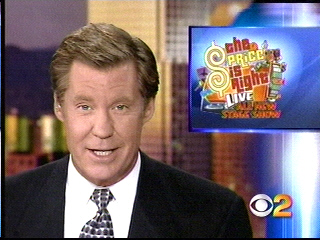 News broadcaster presenting a segment about 'The Price is Right Live' with the show logo displayed in the background.