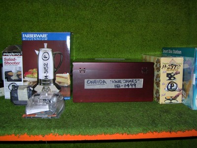 A collection of various kitchen and office items displayed on a shelf, including a Farberware coffee maker, Presto salad shooter, a box labeled 'Oneida - King James,' and a Smart Disc Station, all set against a green background.