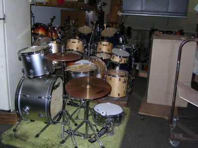 A collection of various drum kits and percussion instruments stored in a studio setting.