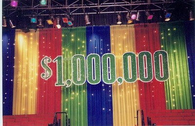 $1,000,000 sign displayed in front of colorful stage curtains with lights.