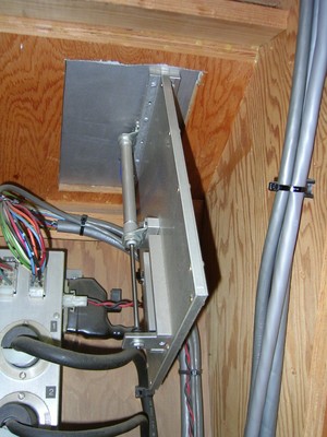 A close-up view of a metallic panel attached to a wooden structure, featuring various electrical wires and components underneath.