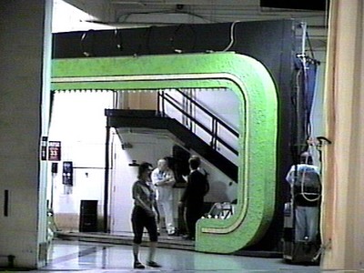 Interior view of the Bob Barker Studio featuring a green and black set piece with a staircase, and two people engaged in conversation.