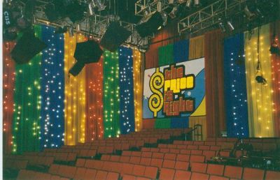 Interior of a colorful studio with vibrant drapes and lights, featuring a sign that reads 'The Price is Right'.