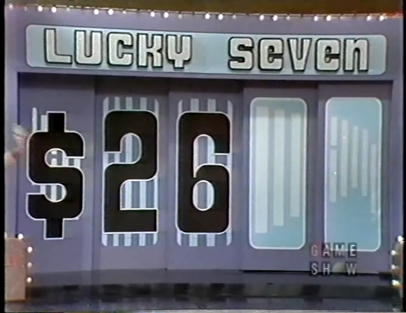A large display board for the game 'Lucky Seven' shows the digits '' prominently in the center, with the game's title at the top. The background is decorated with vertical lines and light bulbs.