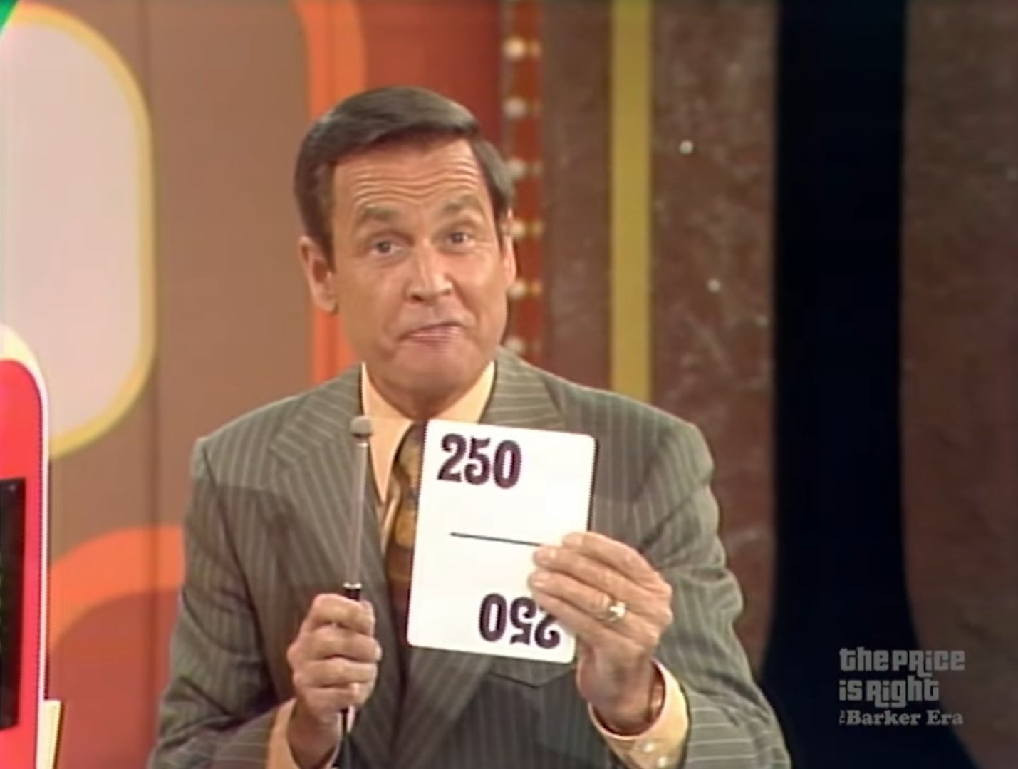 Bob Barker holding a card displaying a range of prices from 250, indicating a game on a television set.