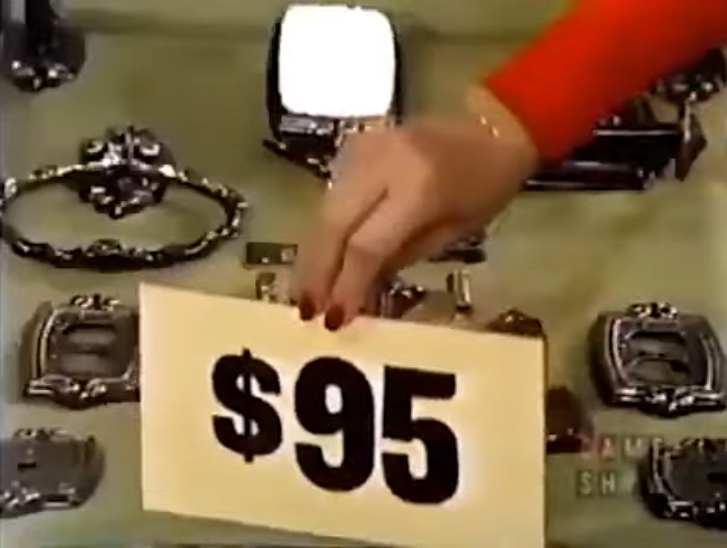 A hand holding a price tag reading '' above various metal home decoration items on a table.