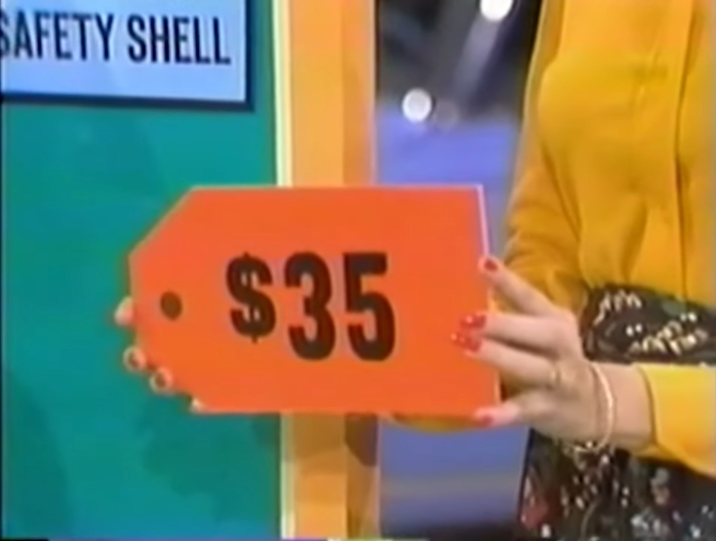  price tag being held alongside a green backdrop in a game show setting.