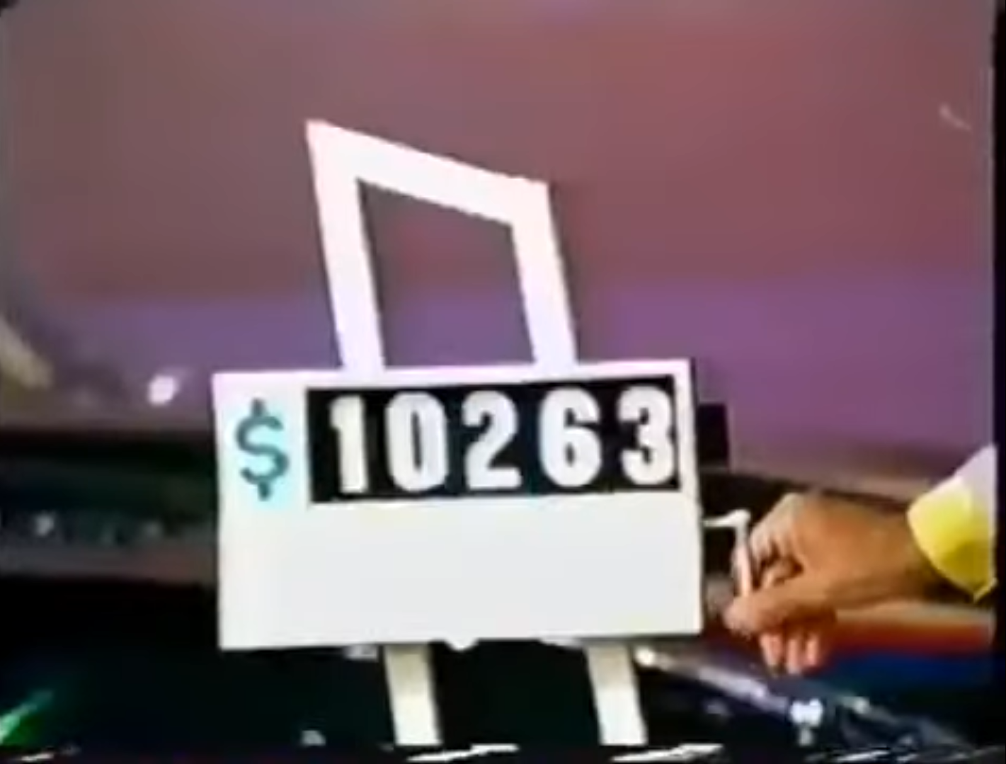 ,263 displayed on a game sign in a car game show, with a hand pulling the lever.