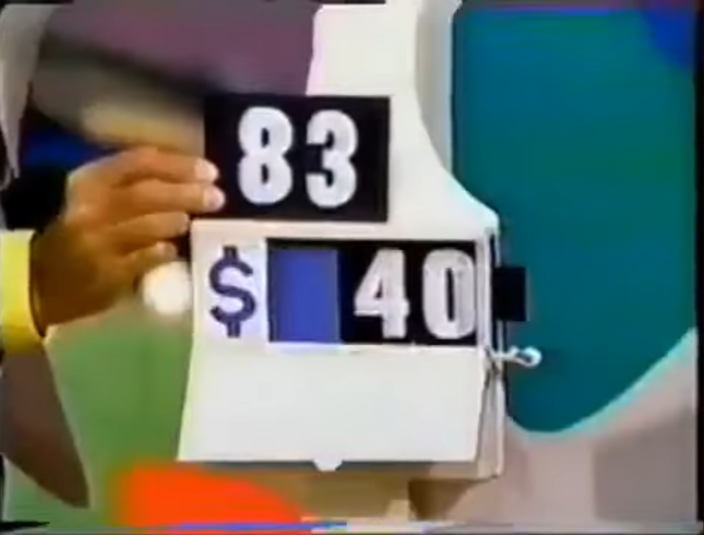 A contestant holds a game board displaying the numbers '83' and a hidden digit for the prize amount of '$_40' during the Golden Road pricing game.