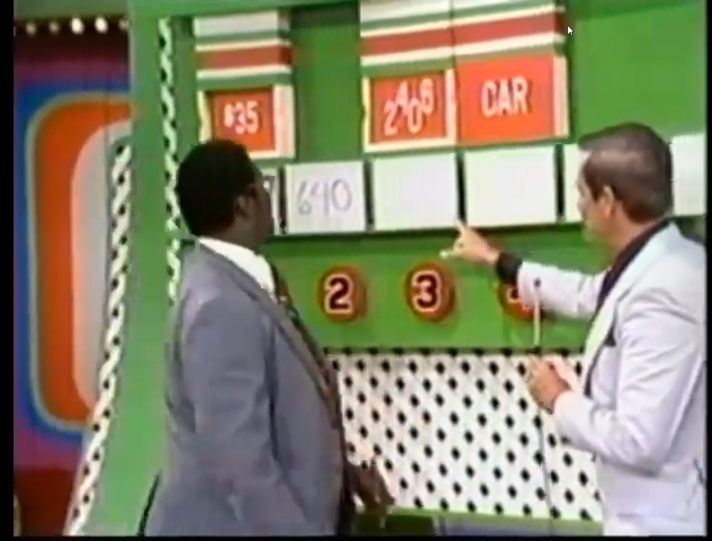 A contestant in a suit appears puzzled while viewing a game board for the 'Ten Chances' game on The Price is Right, featuring displayed prices and a car prize.