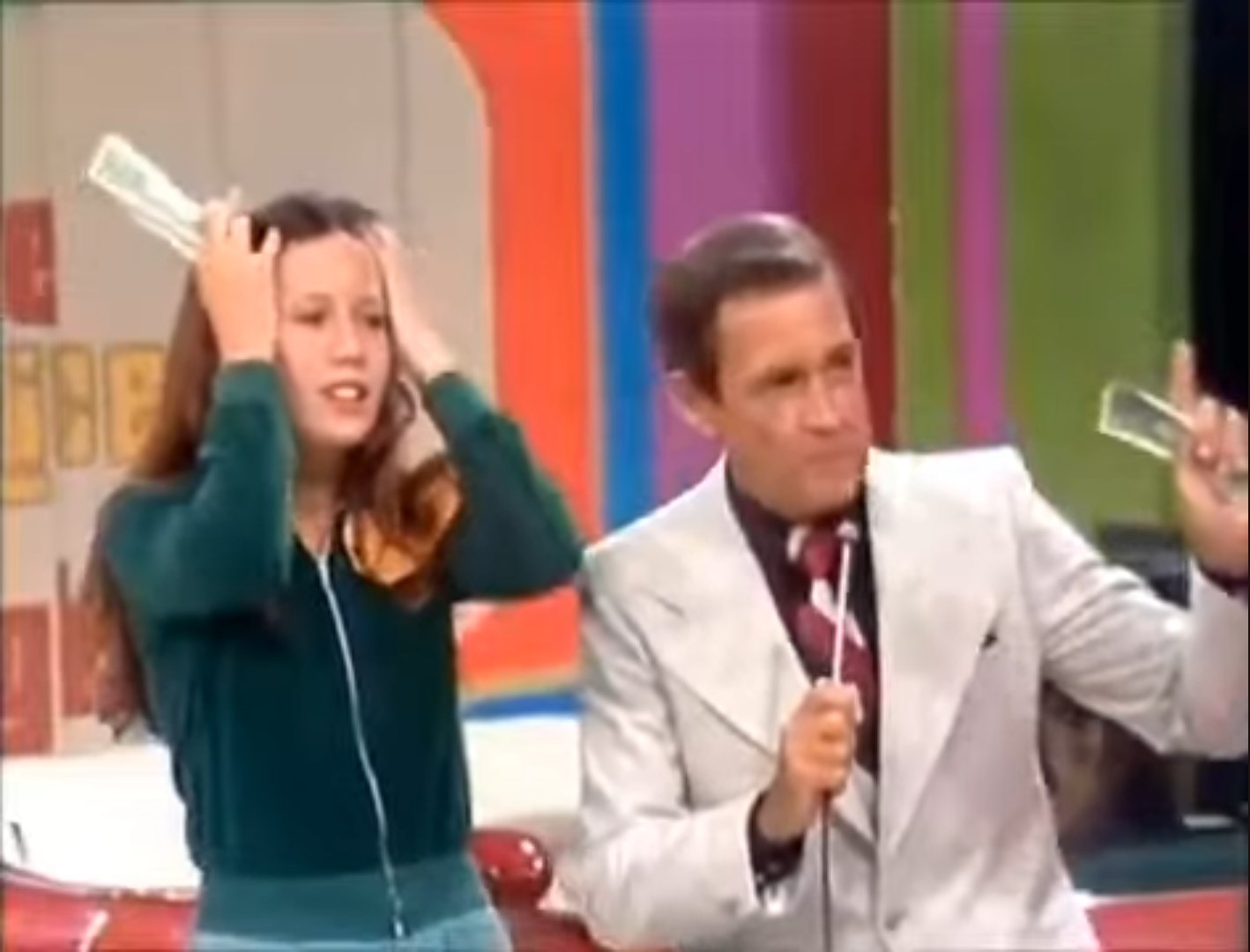 Contestant showing concern while holding cash during the game Lucky Seven on The Price is Right, with the host speaking to her.