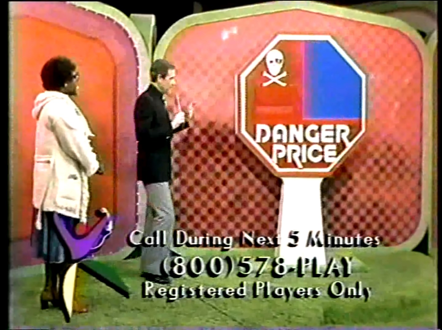 A host stands in front of the 'Danger Price' game display, which features an octagonal sign with the words 'DANGER PRICE' and a skull symbol, while a contestant watches from the side.