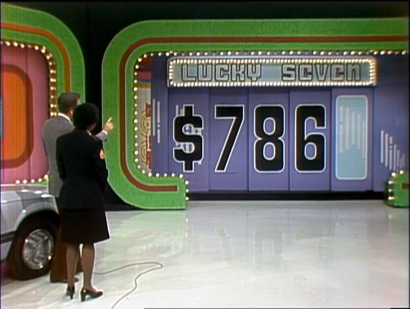 Two contestants participating in the game 'Lucky Seven' with a display showing the price 6.