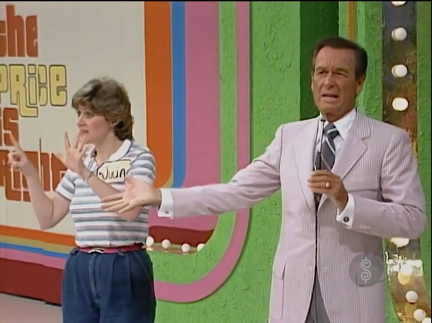 A contestant named Julia is seen on stage with a host, both gesturing towards the audience in a colorful game show set.