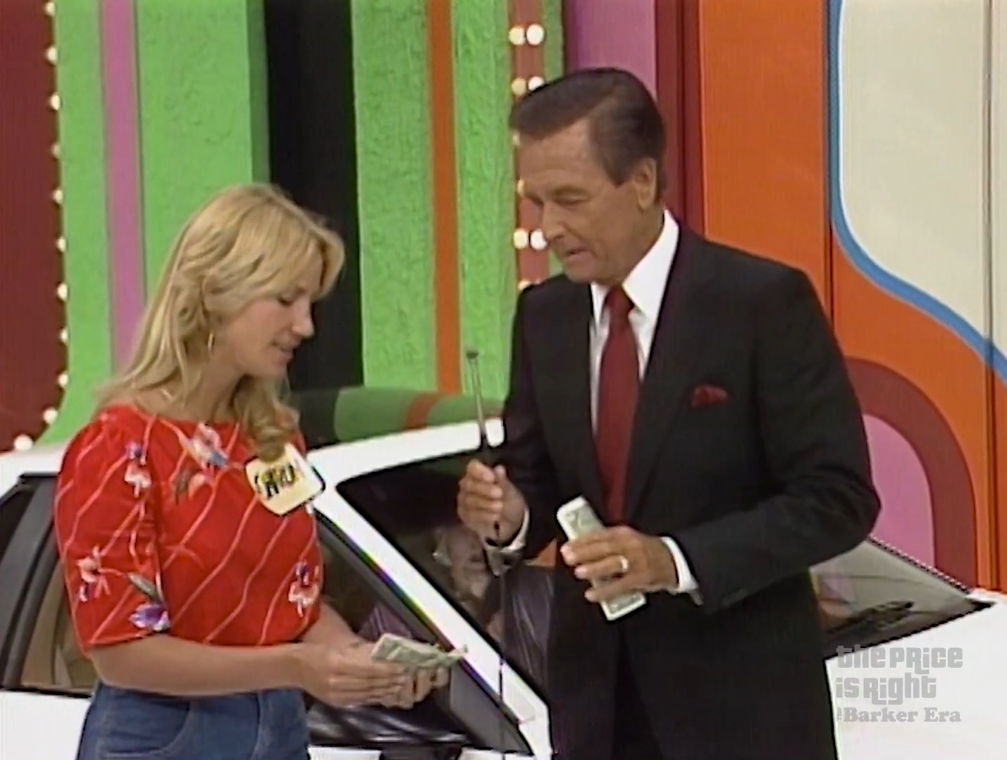 Contestant holds cash while interacting with the host during the game show 'The Price is Right'.