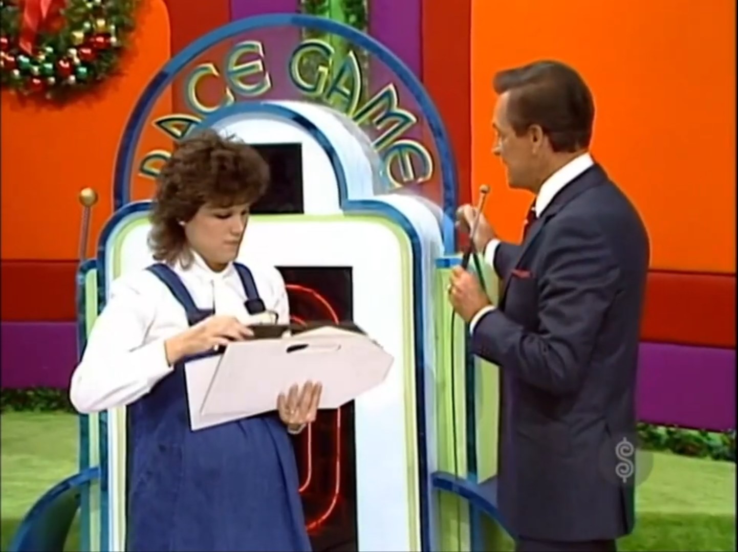 A contestant prepares for the Race Game while Bob Barker explains the rules, showcasing the vibrant game set.